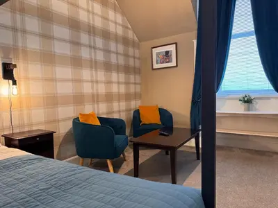 a hotel room with a bed and two chairs and a table at Ernespie House Hotel in Castle Douglas