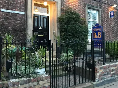 a black fence in front of a house with a bbb sign at Cornerways Guest House in Carlisle