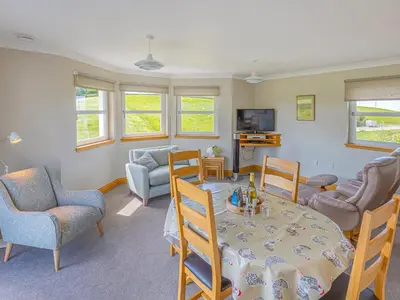 a living room with a table and chairs and a television at The Potting Shed in Challoch