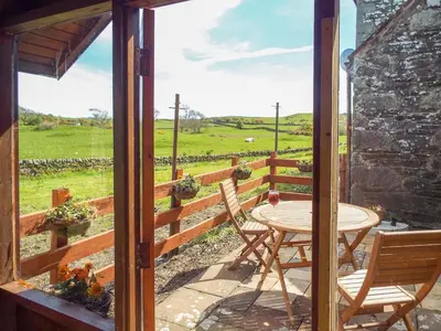 a patio with a table and chairs and a view of a field at The Bothy - Uk5803 in Girthon
