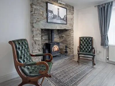 a living room with a stone fireplace and a chair at Callander's High Street in Gatehouse of Fleet