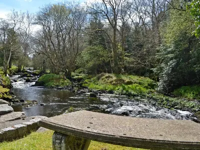 a stone bench sitting next to a river at Anvil in Dalbeattie