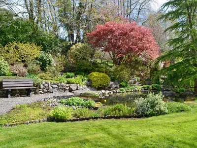 a park bench next to a pond in a garden at Anvil in Dalbeattie