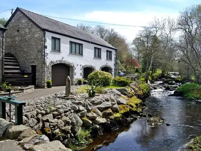a house with a river in front of a building at Waterwheel in Dalbeattie