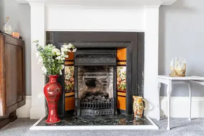 a fireplace with a red vase with flowers in it at Craigmount in Wigtown