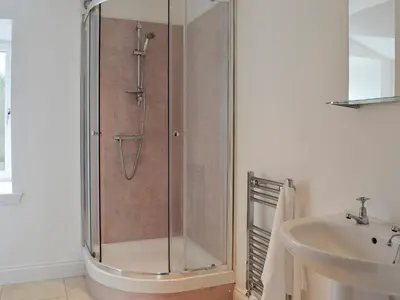 a shower with a glass door next to a sink at Kirroughtree Steading 1 - Uk5859 in Newton Stewart