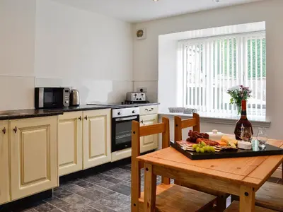a kitchen with a wooden table with a plate of food at Kirroughtree Steading 1 - Uk5859 in Newton Stewart