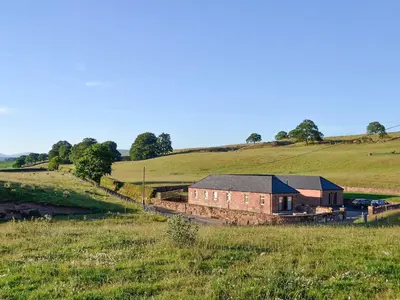 a building on a train track in a field at Liftingstane Dairy Cottage in Closeburn