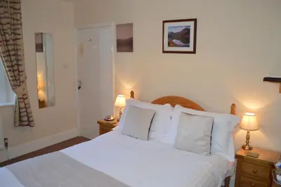 a bedroom with a bed with white sheets and pillows at Beckside Guest House Keswick in Keswick