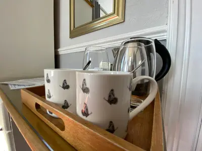 two coffee cups and glasses sitting in a wooden drawer at Goodwin House in Keswick
