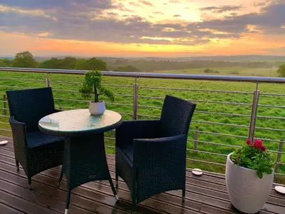 a table and chairs on a deck with a view of a field at Ayrs and Graces - Luxury Bed and Breakfast in Ayr