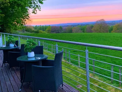 a table and chairs on a deck with a view of a field at Ayrs and Graces - Luxury Bed and Breakfast in Ayr