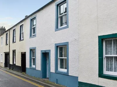 a row of white houses with blue doors on a street at Applegarth in Cockermouth
