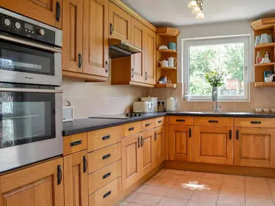 a kitchen with wooden cabinets and a window at Applegarth in Cockermouth