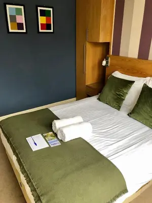 a bed with green sheets and towels on it at Salisbury Guest House in Keswick