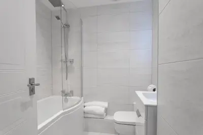 a white bathroom with a toilet and a sink at The Huntington - Donnini Apartments in Ayr