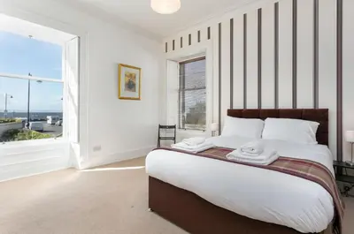 a bedroom with a large bed and a large window at Sea Breeze - Donnini Apartments in Ayr