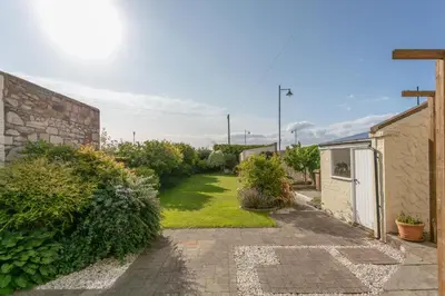 a garden with a pathway leading to a house at Sea Breeze - Donnini Apartments in Ayr