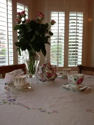a table with a vase of roses and cups and a vase of flowers at Raymonds in Douglas