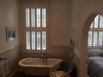 a bathroom with a tub and a bed and windows at Raymonds in Douglas