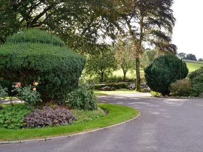 a garden with bushes and trees and a road at Jose's At The Grange in Mockerkin
