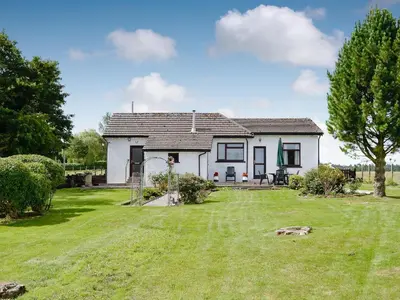 a white house with a large yard at Brae Cottage in Kelton