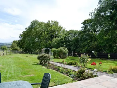 a view of a garden with flowers and trees at Brae Cottage in Kelton