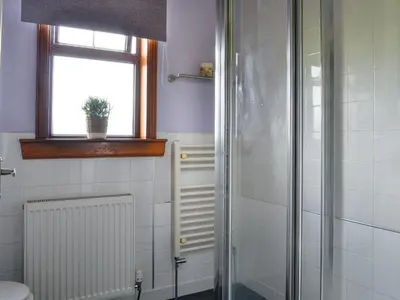a bathroom with a shower and a window at Brae Cottage in Kelton
