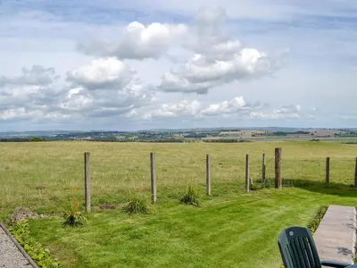 a fence in the middle of a field at Brae Cottage in Kelton