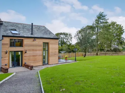 a wooden house with a green lawn in front of it at Holmegarth in Plumbland