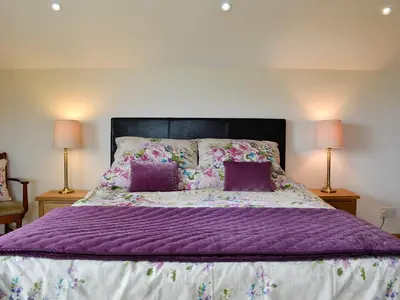 a bedroom with a purple bed with two lamps at Farm Cottage in Cleator