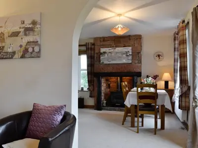 a living room with a table and a fireplace at Rose Cottage in Cleator