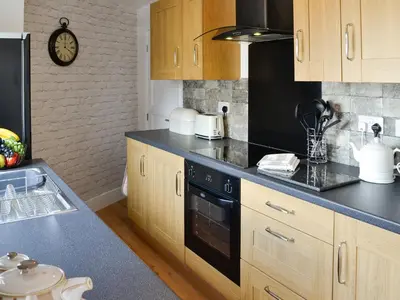 a kitchen with wooden cabinets and a black counter top at Townend Cottage in Aikton