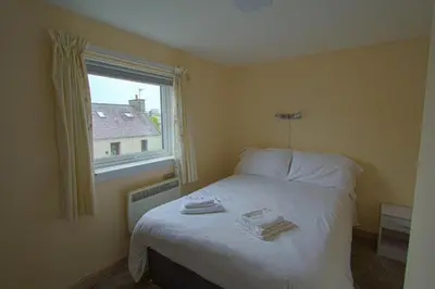a small bedroom with a bed with a window at Harbour Inn Appartments in Garlieston