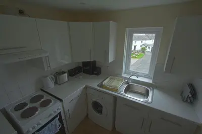 a white kitchen with a sink and a window at Harbour Inn Appartments in Garlieston