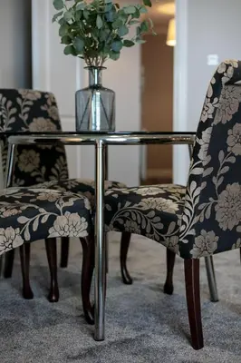 a glass table and two chairs with a vase on top at Harris Retreat - Donnini Apartments in Ayr