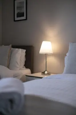 a lamp on a table next to a bed and a couch at Harris Retreat - Donnini Apartments in Ayr