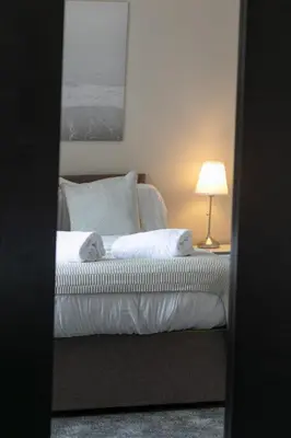 a bedroom with a bed and a lamp on a table at Harris Retreat - Donnini Apartments in Ayr