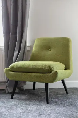 a green chair sitting in front of a window at Harris Retreat - Donnini Apartments in Ayr