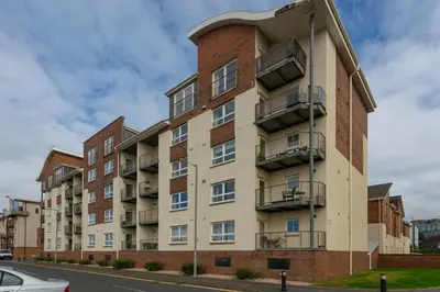 an apartment building with balconies on a street at Harris Retreat - Donnini Apartments in Ayr