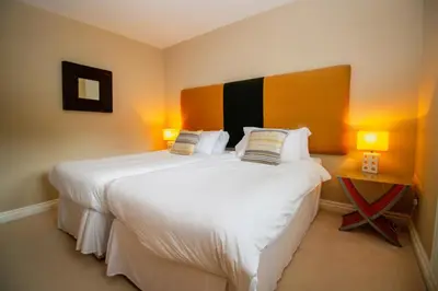 a bedroom with a large white bed with two lamps at Turnberry Apartments in Turnberry