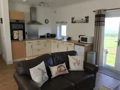 a living room with a couch and a kitchen at Carrick Hills Cosy Croft STL SA-00137-F in Dunure