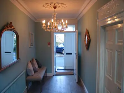 a hallway with a chandelier and a hallway with a door at Osborne House B&B Workington in Workington