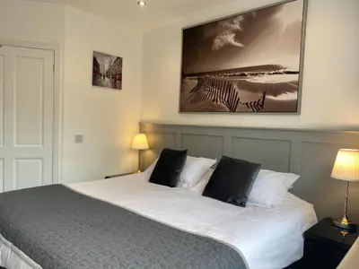 a bedroom with a white bed with two black pillows at Miller House Courtyard in Ayr