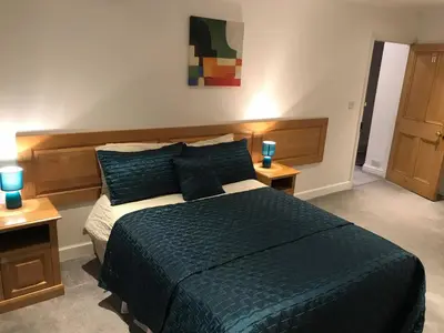 a bedroom with a large bed with two night stands at Vollie House with Hot Tub, Sauna & Log Burner in Penpont
