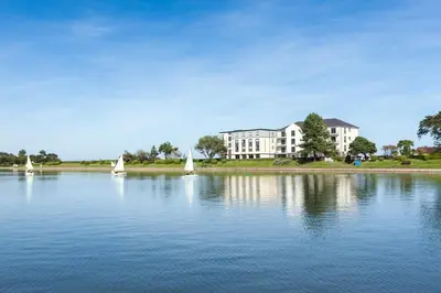 three sailboats on the water in front of a building at Ramsey Park Hotel in Ramsey