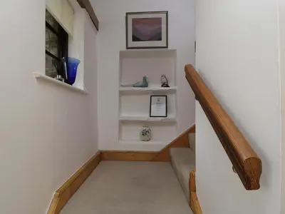 a hallway with a staircase with white walls and white shelves at Holemire Barn in Cockermouth