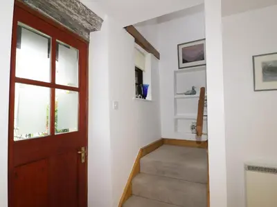 a hallway with a wooden door and stairs at Holemire Barn in Cockermouth