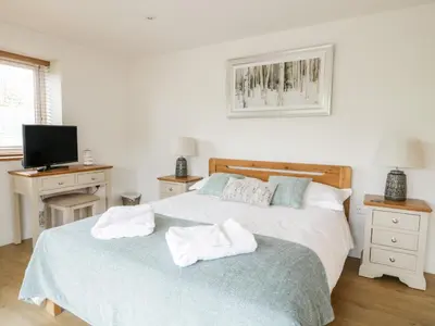 a white bedroom with two beds and a television at Coney Garth Retreat in Beckermet