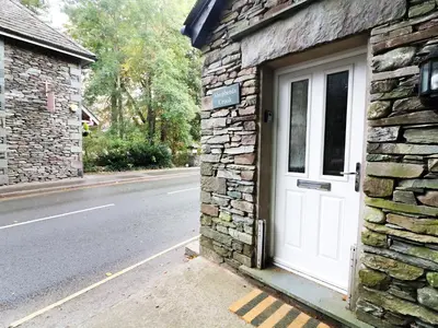 a white door on the side of a stone building at Shepherd's Crook in Ambleside